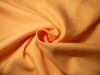 Peach colored plain cotton wavy fabric. Texture, background. template. Lightweight fabric for curtains or bed linen. Poplin, coarse calico, staple, satin, chintz. Folds. Textile. Material