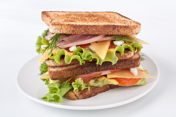 Big  healthy toasted bread, meat, lettuce and cheese sandwich on a white background