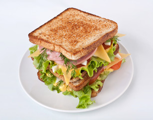 Big  healthy toasted bread, meat, lettuce and cheese sandwich on a white background