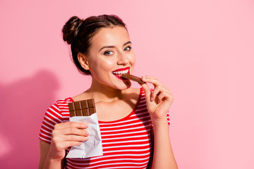 Close-up portrait of her she nice-looking cute charming attractive winsome lovely cheerful girl in striped t-shirt biting tasting eating desirable dessert isolated over pink pastel background - obrazy, fototapety, plakaty