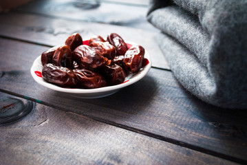 Saucer of date fruits and folded grey blanket