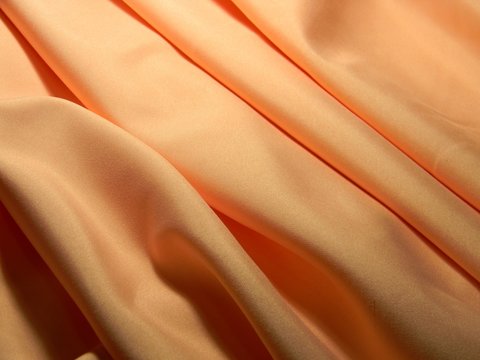 Peach Colored Plain Cotton Wavy Fabric. Texture, Background. Template. Lightweight Fabric For Curtains Or Bed Linen. Poplin, Coarse Calico, Staple, Satin, Chintz. Folds. Textile. Material