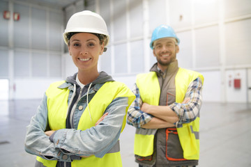 Male and female concstruction coworkers in warehouse looking at camera