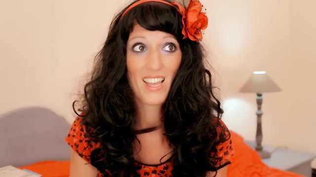 A pretty silly girl, sitting on the bed in a colorful bedroom, smelling something bad, waving her hand while talking. Interior sit-com setting. Close-up shot.