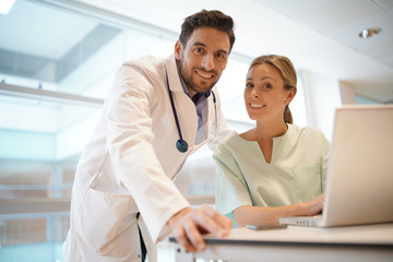 Doctor and nurse smiling at camera in hospital office