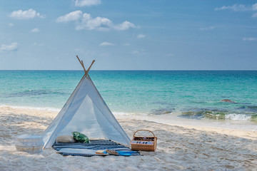 romantic white picnic tent on white sand beach with crystal clear water and blue sky at background
