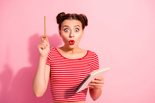 Portrait of her she nice cute charming attractive amazed teen girl wearing striped t-shirt pointing pencil up copybook isolated over pink pastel background