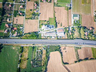 vertical air view of agricultural green fields and lands landscape near a highway and cars on the road