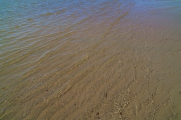 The waves beat at the beach with sand and reflection of sunlight in summer morning. Nature background concept.