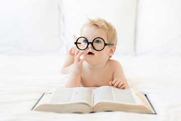 Baby boy with glasses reading book