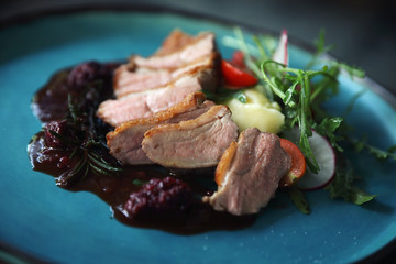 Duck confit with salad , baked apple and raspberry sauce served on wooden table