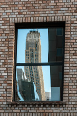 Reflection of the skyscraper in the window of the typical Manhattan house. New York City, USA.