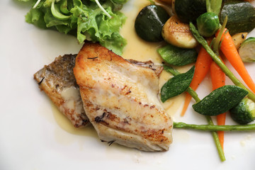 Sea bass fillet with grilled vegetables and salad on wooden table