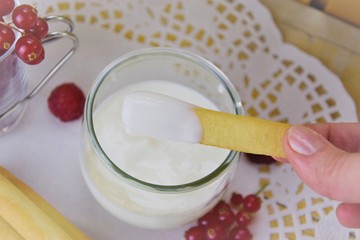 Breezy summer breakfast, yogurt and red berries, hand of woman