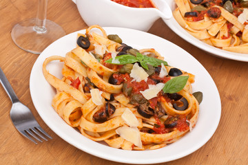 Linguine pasta with fresh tomato puttanesca sauce, grated parmesan  cheese and basil