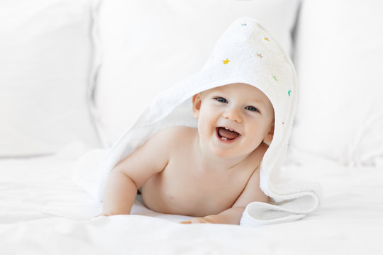 Laughing baby boy wrapped in towel after bath