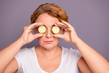 Close up photo beautiful amazing mature she her lady spa procedures hold cucumber specs slices hide eyes  nature treatment ideal condition under eyes bags wear white t-shirt isolated grey background