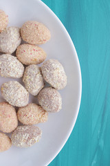 Chocolate egg candies in white bowl on blue background