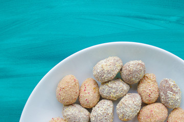 Chocolate egg candies in white bowl on blue background