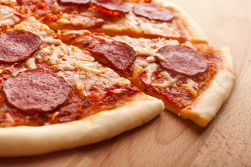 sliced whole salami pizza on wooden table