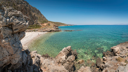 Fototapeta na wymiar Lonely bay of Kakia Langada with a transparant green sea under a blue sky and rocks in the foreground on the island Kythira, Greece