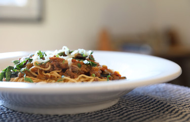 spaghetti Bolognese with minced beef and tomato sauce garnished with parmesan cheese and basil , Italian food