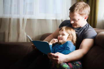Father reading a story to his child daughter. happy family time together at home.