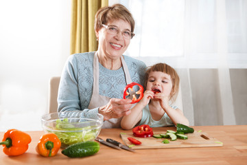 Grandma and child daughter are preparing the vegetables in salad in the kitchen. Healthy Lifestyle food.