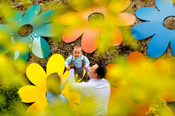 Young beautiful parents posing in park with their little baby boy