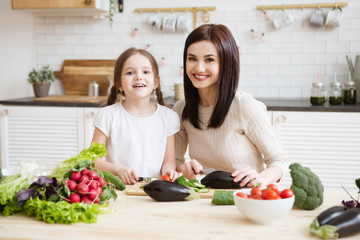 Obraz na płótnie Canvas Mother and daughter in preparing healthy vegetables salad together in the kitchen. Help children to parents. 
