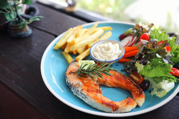 Roasted salmon steak , baked salmon with salad fresh vegetable pm wooden table