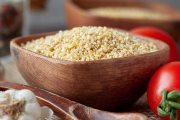Uncooked raw bulgur wheat grains in wooden bowl