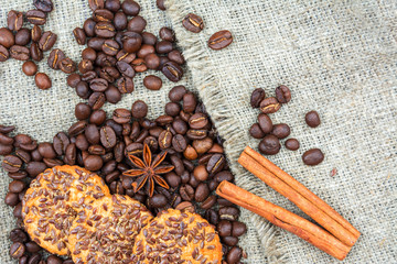 Coffee beans, a slice of lemon, cinnamon sticks and cookies are on the old linen fabric.