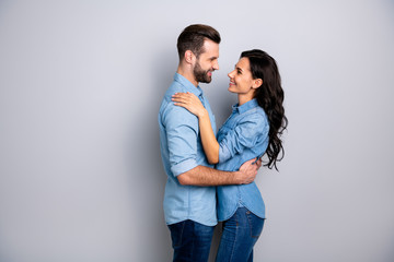 Affection. Profile side view photo of handsome casual spouses looking into eyes satisfied delighted enjoying society dressed in blue denim shirts isolated over argent background
