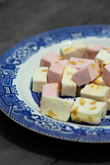 Pink and white nougat on a blue and white plate with a wood background