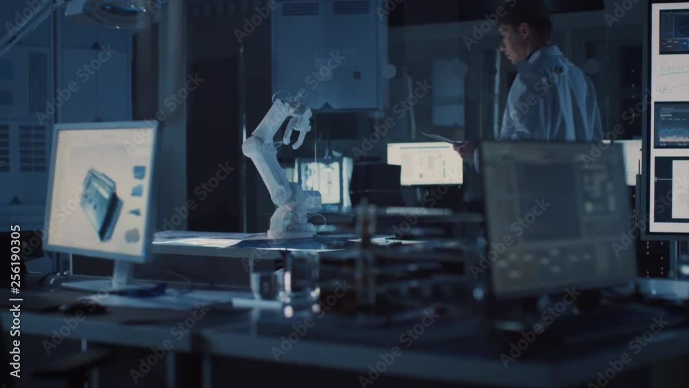 Fototapete Professional Heavy Industry Robotics Engineer Wearing White Coat Holding Tablet Computer Walks Through Laboratory. Facility Full of Computers, Various Industrial Design Components and with Robotic Arm
