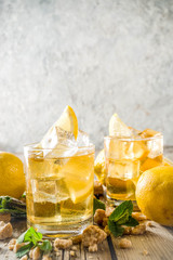 Lemonade or iced summer tea, with fresh lemon slices, sugar and mint leaf, rustic wooden table, copy space