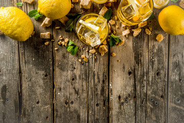 Lemonade or iced summer tea, with fresh lemon slices, sugar and mint leaf, rustic wooden table, copy space