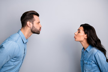 Blind dating. Profile side photo close up of cute funny shy spouses sending air kisses closing eyes showing feelings dressed in fashionable blue jackets isolated on ashy-gray background