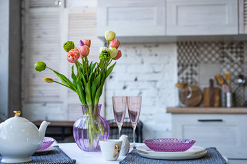 Glass vase with bouquet of beautiful tulips on brick wall background