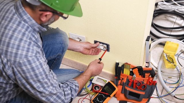 Electrician technician worker with the multimeter it measures the voltage in an electrical socket in a residential system. Construction industry. Building. Footage. 