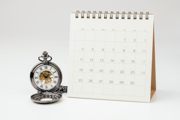 Vintage pocket watch with white clean desktop calendar on white background using as time passing, time management, year change or deadline concept