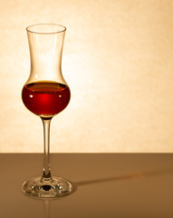 a glass of brandy is on the table against a dark background