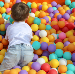 Fototapeta na wymiar The boy plays in colorful balls on the attraction