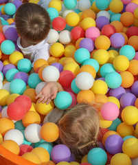 Fototapeta na wymiar Boy and girl playing in colorful balls on attraction