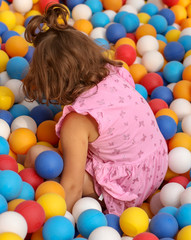 Fototapeta na wymiar Girl playing in colorful balls on the attraction