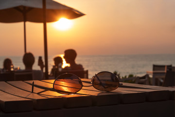 Glasses laying on the table against the sunset.People sitting at the table against sunset on the sea.Concept of rest, relaxation, vacation. sea sunset.