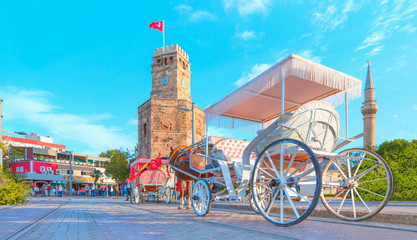 A traditional phaeton is waiting for customers by a Antalya clock tower at Republic Square -...