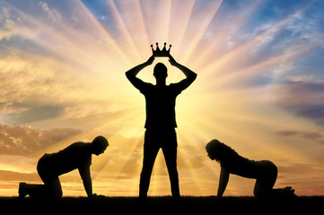 Silhouette of a woman and a man worshiping a man who puts a crown on his head against the sunset - obrazy, fototapety, plakaty