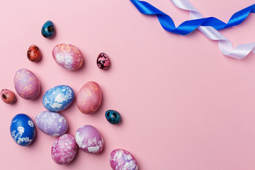 Easter eggs with white and blue ribbon on pink background